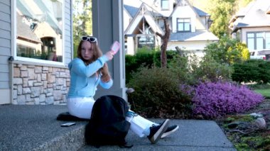 Çekici genç bir kadın kampüs çimlerinin üzerinde otururken dizüstü bilgisayar kullanıyor. Doğadaki derslere hazırlanan güzel kız öğrenci arkadaşları uzakta otururken bulanıklaştı. 