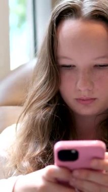 Havalimanında oturmuş uçuşunu bekleyen hoş ve tapılası beyaz bir kadın. Büyüleyici ve çarpıcı bir genç bayan akıllı telefon kullanıyor, iletişim kuruyor, gülümsemekten zevk alıyor. Seyahat konsepti. Yüksek kalite 4k