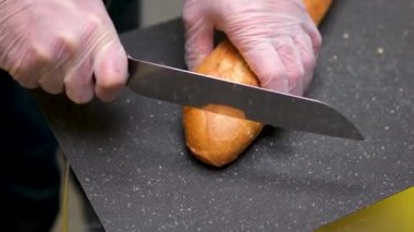 Bir el, mutfakta bir somun ekmeği tahta kesme tahtasıyla keser. Yüksek kalite 4k görüntü