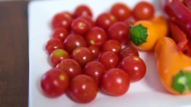 Kırmızı dolma biber, canlı kırmızı ve sarı kiraz domateslerinin üzerinde yavaşça döner. Yüksek kalite 4k görüntü