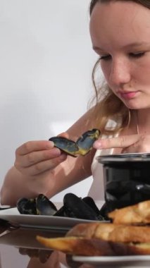 Küçük bir kızın portresi masaya oturur ve mutfak arka planında kızarmış ekmek ve peynirli domates çorbası içer. Çocuk yemek yerken parmaklarını yalıyor. Çocuk öğle yemeği yiyor. Yüksek kalite 4k görüntü