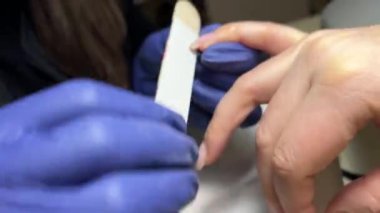 Kadın eli ve manikür aletleri, güzellik salonunda manikür yapma süreci. Güzellik salonunda çivi bakım prosedürü. Tırnak etlerini kesen yetenekli bir manikürcünün eldivenli elleri. Spa gövdesini kavra