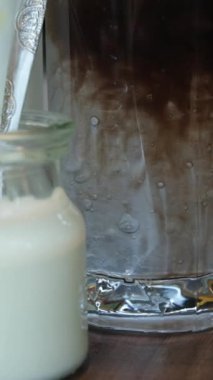 Yavaş yavaş soya sütü bir bardağa dökülüyor. Soya sütü ya da fasulye sütü bir cam bardağa dökülür. Soya sütü sağlıklı vejetaryenler için bitki bazlı bir içecek olarak kabul edilir. Asya sütü içeceği