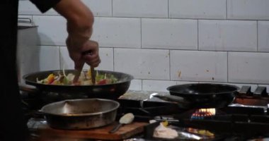 Şef Kızarmış Sebzeleri Açık Mutfaktaki Alevli Tavada Karıştırıyor. Flambe Tekniğini Kullanarak Yemek Pişiren, Sıcak Yağ ve Alkolü Bir Tavada Ateşleyen Kişi. Süper Yavaş Hareketi Kapat 