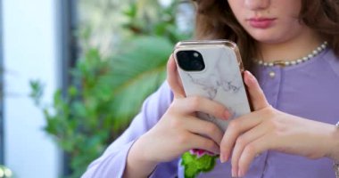 Kanepede oturan genç bir kadın cep telefonu kullanıyor, elinde dizüstü bilgisayarla mutlu bir kadın cep telefonuna bakıyor mobil uygulamalarda internetten alışveriş yapıyor ecommerce ürünleri sipariş ediyor ya da sosyal medyayı kontrol ediyor..