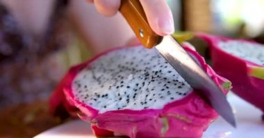 Pembe arka planda izole edilmiş bir tabakta iki yarım ejderha meyveli pitahaya. Yüksek kalite 4k görüntü