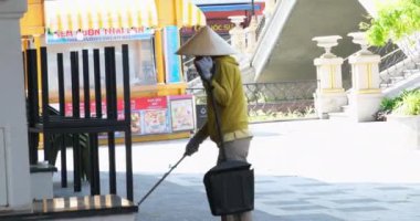 Sokak temizleyicisi eski kuru yaprakları temizliyor. Şehir yolu asfaltını kapatın. Temizlikçi kadın servisi. Temizlikçi temiz kaldırım. Şehir işçi bakım parkı. Adam dışarıda çalışıyor. Vietnam Ho Chi Minh Şehri 01.30.2025