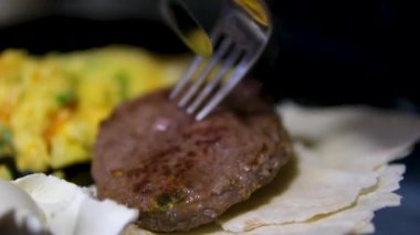 Bıçak ve çatalla pirzola kes. Lavaş omletle yemek ye. Yüksek kalite 4k görüntü