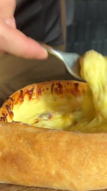Bir adam Adjarian Khachapuri yiyor. Peynirli ve yumurtalı turta. Yüksek kalite 4k görüntü
