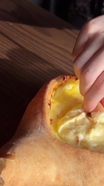 Kadınların elleri Adjarian Khachapuri 'den bir parça koparıp erimiş peynir ve yumurta sarısı karışımına batırıyor. Geleneksel Gürcü yemek kavramının tadını çıkarıyorum. Yüksek kalite 4k görüntü
