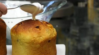 Paskalya pastası süslemesi. Pasta şefinin elleri şeker süslemelerini beyaz şeker şekerine yerleştirir. Katolik ve Ortodoks bayramları masası. Kremalı Paskalya Pastası. Paskalya pastasına krema sür.
