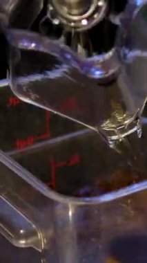 Barmen, elleri yakın plan, alkollü kokteyl hazırlıyor, ölçülmüş bardağa dökülüyor ve karıştırıcıya dökülüyor. Dikey format. Yüksek kalite 4k görüntü