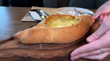 Garson, geleneksel Gürcistan usulü çiğ yumurtalı peynirli ekmek tabağı olan Adjarian Khachapuri 'yi müşteriler için hazırlamış. Yüksek kalite 4k görüntü
