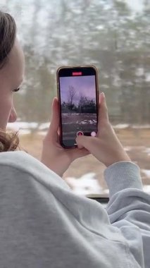 Manzaralı otobüs gezisi çarpıcı manzaralar ve bölgedeki popüler turistik yerler. - Evet. Bir kız kışın cep telefonuyla video çekiyor.