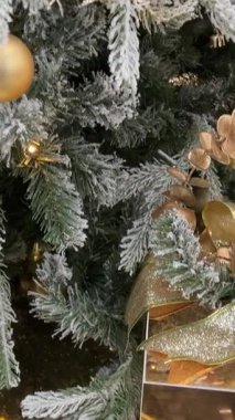 Bir Noel ağacını ışıltılı ışıklarla süslemek, renkli süsler ve eve tatil ruhunu getiren bir yıldızın olduğu neşeli bir sahne. Yüksek kalite 4k 