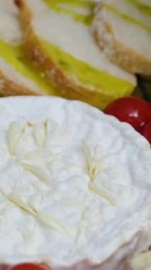  Konum. Bir ev hanımı mutfak masasındaki salataya zeytinyağı ekler. Genç bir kadın çeşitli sebze ve peynirlerle zeytinyağı döküyor. Domatesli ve kızarmış ekmekli camembert peyniri pişir.