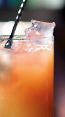 Bir bardak Aperol Spritz kokteyli. Renkli bir arka planda. Aperol Spritz 'i kokteyl kaşığıyla karıştırmak. Statik çekim. Yüksek kalite 4k görüntü