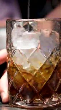Profesyonel bir barmene yakın plan, alkol kokteyli ile profesyonel kristal uzun süreli buz küplerini bardaki veya disko kulübündeki müşterilerle karıştırıyor. Profesyonel barmen ustaca yaratıyor.