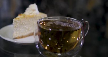 Kurabiye ve kek gibi lezzetli hamur işleriyle dolu cam masa. Yanında da iki çay fincanı var. Çay saati için mükemmel. Yüksek kalite 4k görüntü