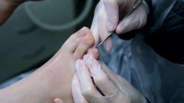 Pedikür ustası küçük ayaklı bir kıza temizlik ve masaj yapar. Bir prosedür sırasında güzellik salonunda kadın güzelliğiyle ilgilenmek. Ayak ve ayak parmaklarının derisi yakın plan.