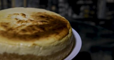 Çelik kek servis aletini dikkatlice kaldırırken ve tüm yuvarlak, yumuşak, fırınlanmış cheesecake tatlısının ilk üçgen dilimini bir tabakta çıkarırken. Yüksek kalite 4k görüntü