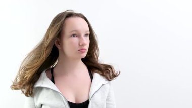 Çekici bir sarışının uçan saçının yavaş hareketi. Gri arka plan. Kadın rüzgar stüdyosu