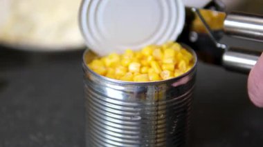 Top View Man 'in elleri mısır kavanozunu açıyor. Koyu arkaplanda izole edilmiş metal kavanozdaki konserve mısır. Konserve açacağıyla bir konserve kutusu aç.