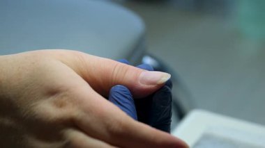Güzellik salonundaki manikür ustasının manikür adım adım bütün hareketleri tırnak derisi lekesi temizleme jöle güçlendirici kadınların ellerini mavi eldivenlerle güçlendirme öz bakım sağlığına. Yüksek kalite 4k görüntü