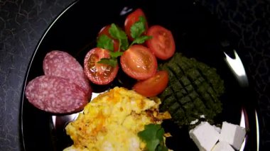 Omlet sosisli, domatesli makarna pesto ve tabakta feta öğle yemeği siyah tabaklar. Yüksek kalite 4k görüntü