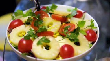 Salata üzerine ananas, domates, kişniş ve bitkilerle zeytinyağı serpiştir. Yüksek kalite 4k görüntü