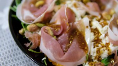 Sebzeli, jambonlu, peynirli, fındıklı, salata karışımlı, mikro yeşil ve diğer malzemeleri koyu renkli modern tabakta bulunan taze lezzetli yazarlar salatası. Yüksek kalite 4k görüntü