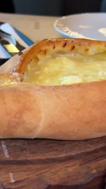 Garson, geleneksel Gürcistan usulü çiğ yumurtalı peynirli ekmek tabağı olan Adjarian Khachapuri 'yi müşteriler için hazırlamış. Yüksek kalite 4k görüntü