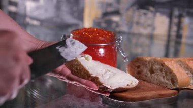 Mans elleri bir kaşık kırmızı havyarı bir parça ekmeğin üzerine koyar. İki kare düzenleniyor. Yakın plan. - Evet. Yüksek kalite 4k görüntü