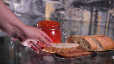 Mans elleri bir kaşık kırmızı havyarı bir parça ekmeğin üzerine koyar. İki kare düzenleniyor. Yakın plan. - Evet. Yüksek kalite 4k görüntü