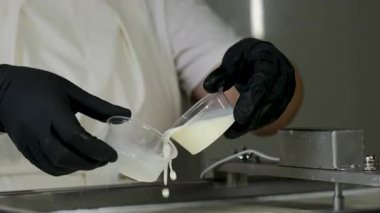 Kauçuk eldivenli, tanınmayan kadın fabrika işçilerinin elleri geleneksel peynir yapan mozzarella ve kakovala peynirinin seri üretimini esnetiyor. Yüksek kalite 4k