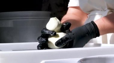 Kauçuk eldivenli, tanınmayan kadın fabrika işçilerinin elleri geleneksel peynir yapan mozzarella ve kakovala peynirinin seri üretimini esnetiyor. Yüksek kalite 4k