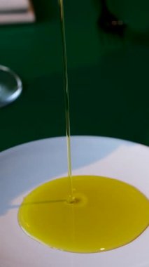 Beyaz bir tabağa zeytinyağı dök. Kadın eli yiyeceğe yağ döker. Yemek pişiren kadın. Sağlıklı yemek. Şef vejetaryen yemeği pişiriyor. Organik sağlıklı sıvı yağ akıyor. Yüksek kalite 4k görüntü
