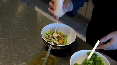 Sebzeli bir kase salata yapmak yeşillik, mayonez sosu, salatalık havucu, avokado ve mısır unu eldivenle hazırlamak, salata aşçısını elleriyle süslemek. Yüksek kalite