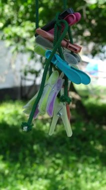 Kız çamaşırları çamaşır makinesinde yıkıyor ve çamaşırları çamaşır ipine asıyor. Bahçede güneşli bir gün. Çamaşır askısında renkli kumaş havlular, yeşil çimenler..