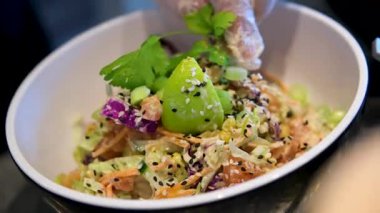 Sebzeli bir kase salata yapmak yeşillik, mayonez sosu, salatalık havucu, avokado ve mısır unu eldivenle hazırlamak, salata aşçısını elleriyle süslemek. Yüksek kalite