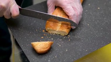 Özel bıçakla taze buğday ekmeği keserken yakın çekim. Kahvaltı ya da öğle yemeği için hazırlık. Yemek ve içecek konsepti 4K görüntüler. Yüksek kalite 4k görüntü