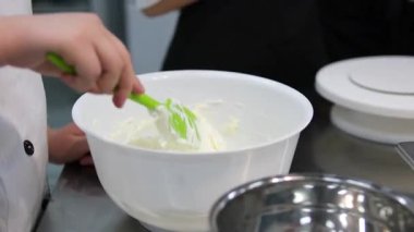 Şekerci yumurtaları şeker ve unla metal bir kasede çırpar. Krema bisküvi yapmak için kırbaçlanır. Şekerleme tatlısı yapma konsepti. Metalik kase kremi