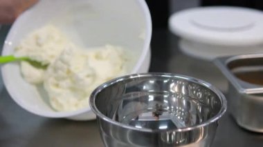 Süzme peynir ya da mutfak masasındaki metal kasede çiftçi peyniri. Taze beyaz peynir karıştıran bir kadın. Yaklaşın, ağır çekim.