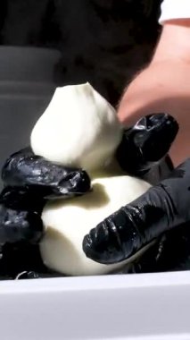 Kauçuk eldivenli, tanınmayan kadın fabrika işçilerinin elleri geleneksel peynir yapan mozzarella ve kakovala peynirinin seri üretimini esnetiyor. Yüksek kalite 4k