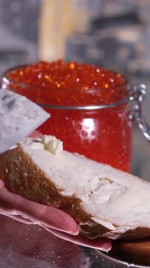 Mans elleri bir kaşık kırmızı havyarı bir parça ekmeğin üzerine koyar. İki kare düzenleniyor. Yakın plan. - Evet. Yüksek kalite 4k görüntü