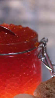 Mans elleri bir kaşık kırmızı havyarı bir parça ekmeğin üzerine koyar. İki kare düzenleniyor. Yakın plan. - Evet. Yüksek kalite 4k görüntü