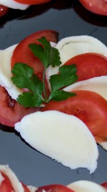 Mozzarella, vişneli domates ve fesleğenli Caprese salatası, daire şeklinde dönüyor. Dikey video. Yüksek kalite 4k görüntü