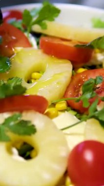 Salata üzerine ananas, domates, kişniş ve bitkilerle zeytinyağı serpiştir. Yüksek kalite 4k görüntü