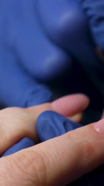 Güzellik salonundaki manikür ustasının manikür adım adım bütün hareketleri tırnak derisi lekesi temizleme jöle güçlendirici kadınların ellerini mavi eldivenlerle güçlendirme öz bakım sağlığına. Yüksek kalite 4k görüntü