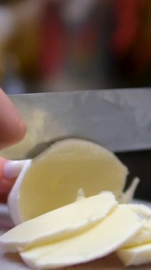 Taze mozzarella toplarını tahta kesme tahtasında küçük küplere ayırmak. Yüksek kalite 4k görüntü